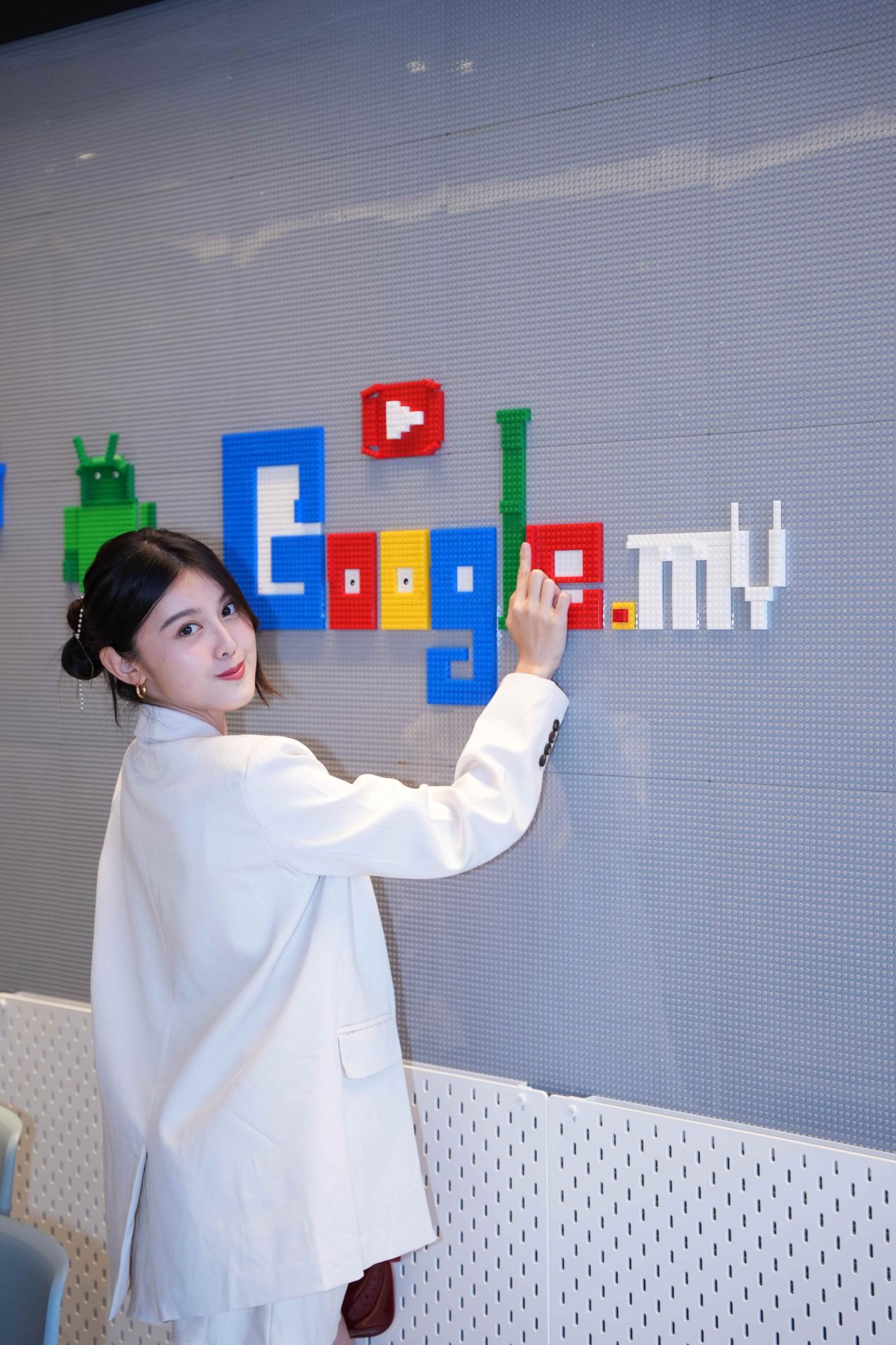 Sherlyn smiling and pointing at a colourful brick wall